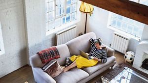 Mature woman on sofa with laptop and headphones