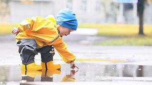 boy playing outdoors in puddles