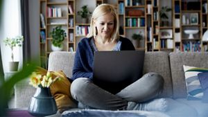 A woman sat on sofa, working on laptop.