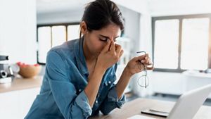 Women looking stressed whilst working at table on a laptop