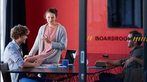 Three people sat in a boardroom, engaged in an informal discussion