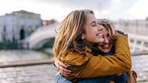 two people hugging and smiling outdoors