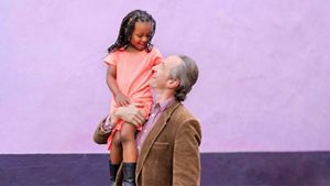 Person holding child on their shoulder with purple background