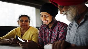 young man showing his mature parents a mobile phone