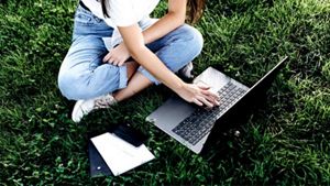 person sitting down on grass on her laptop