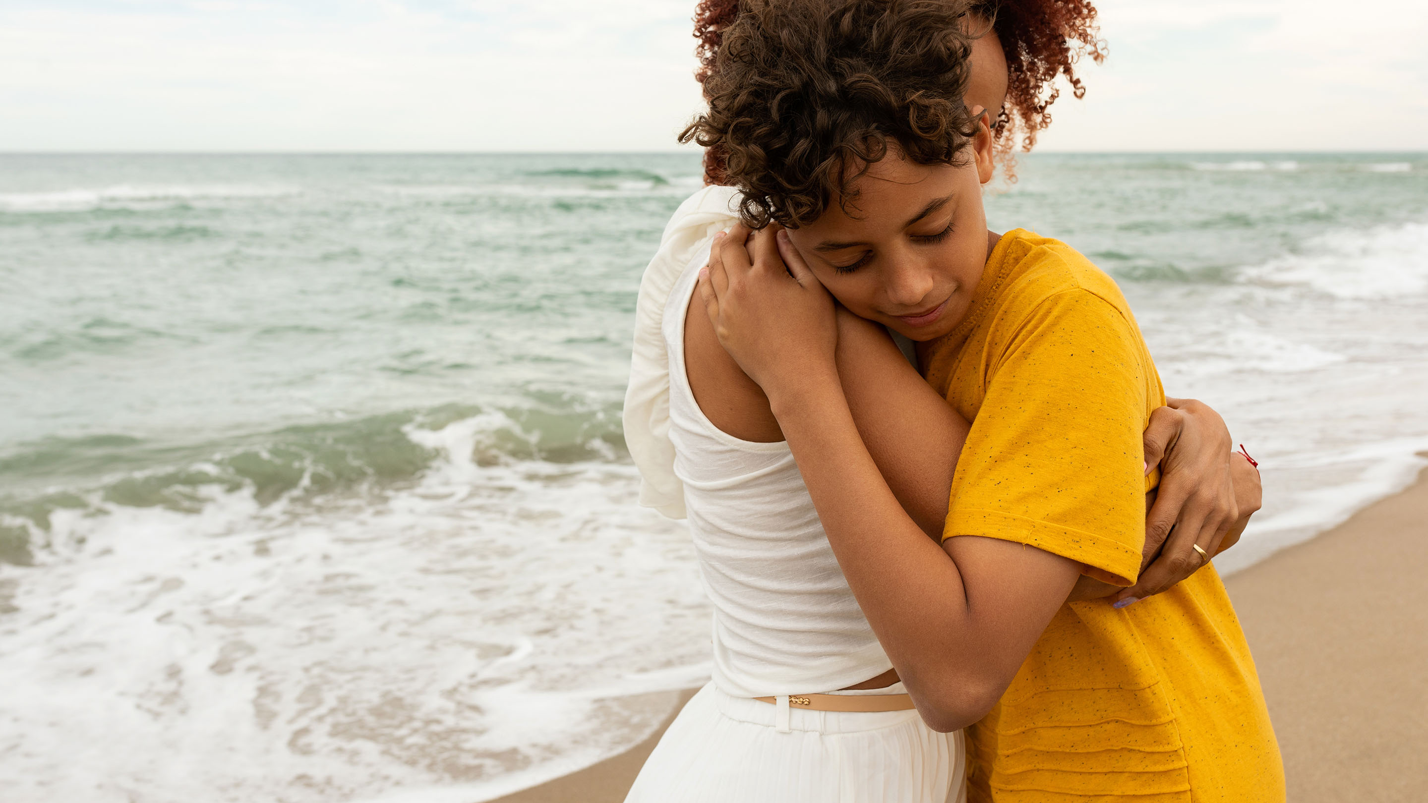 Adult and child hugging on the beach