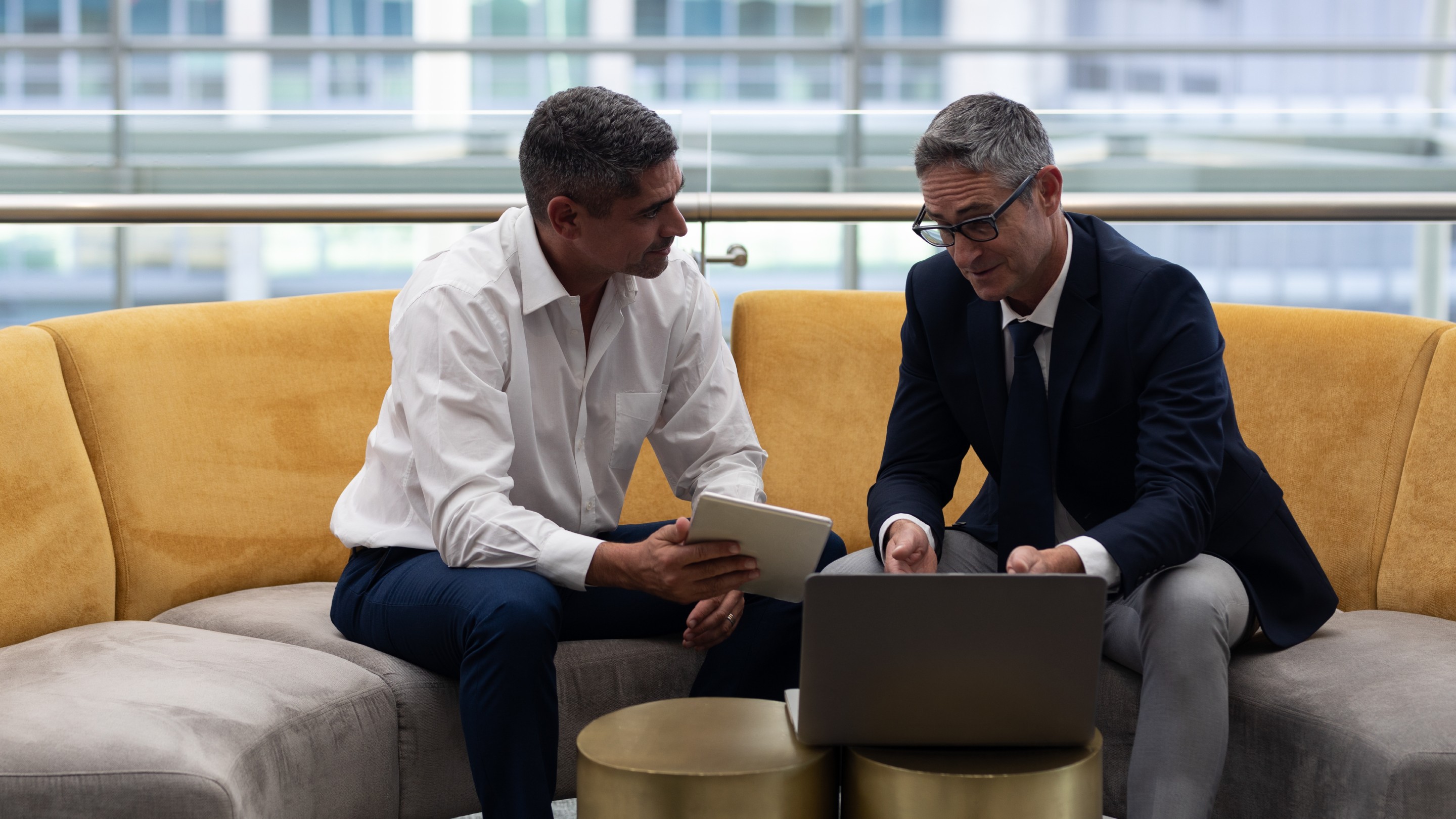 Businessmen talking over a laptop while sitting on the sofa