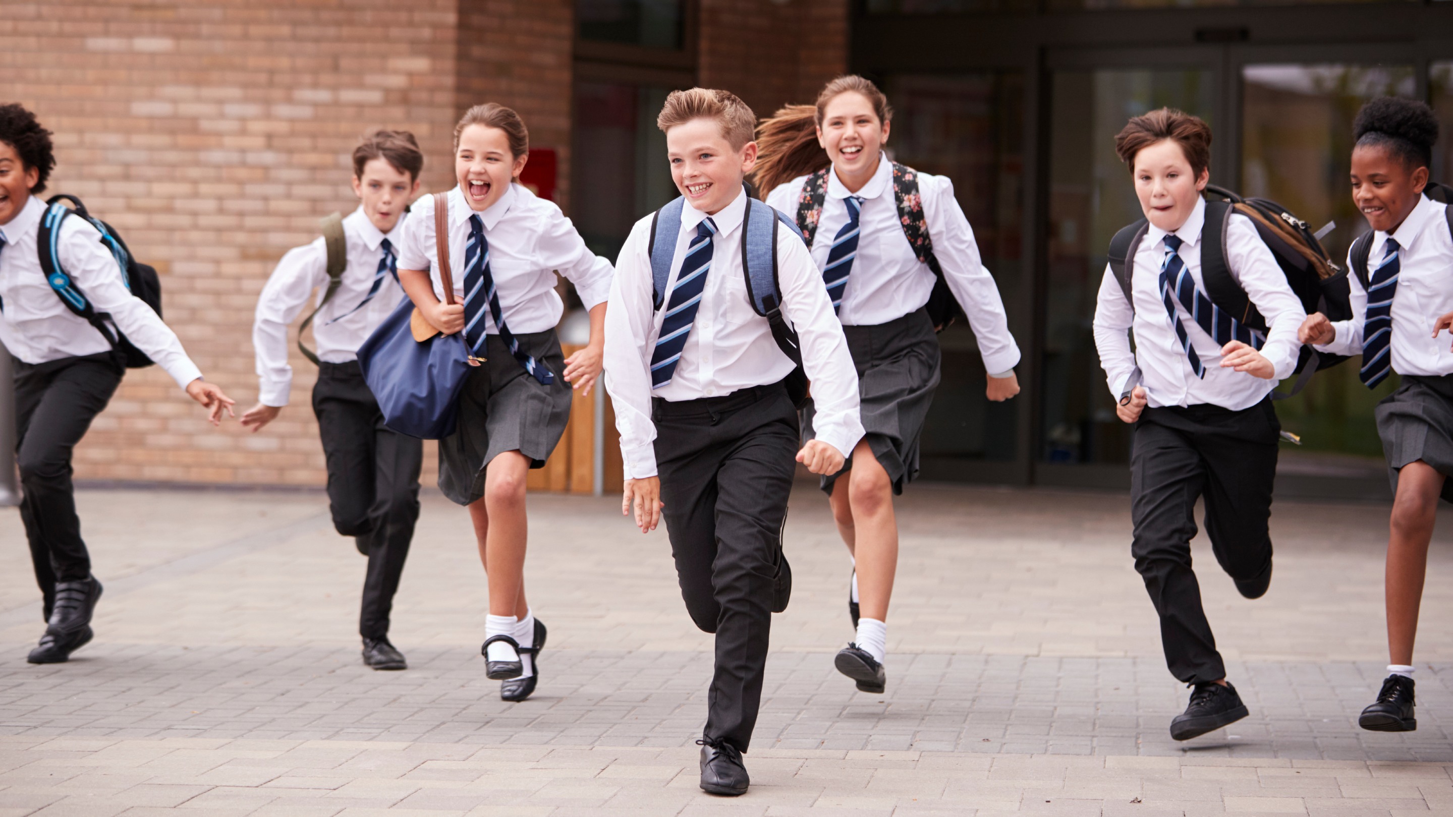 Group of students wearing uniform running out of school