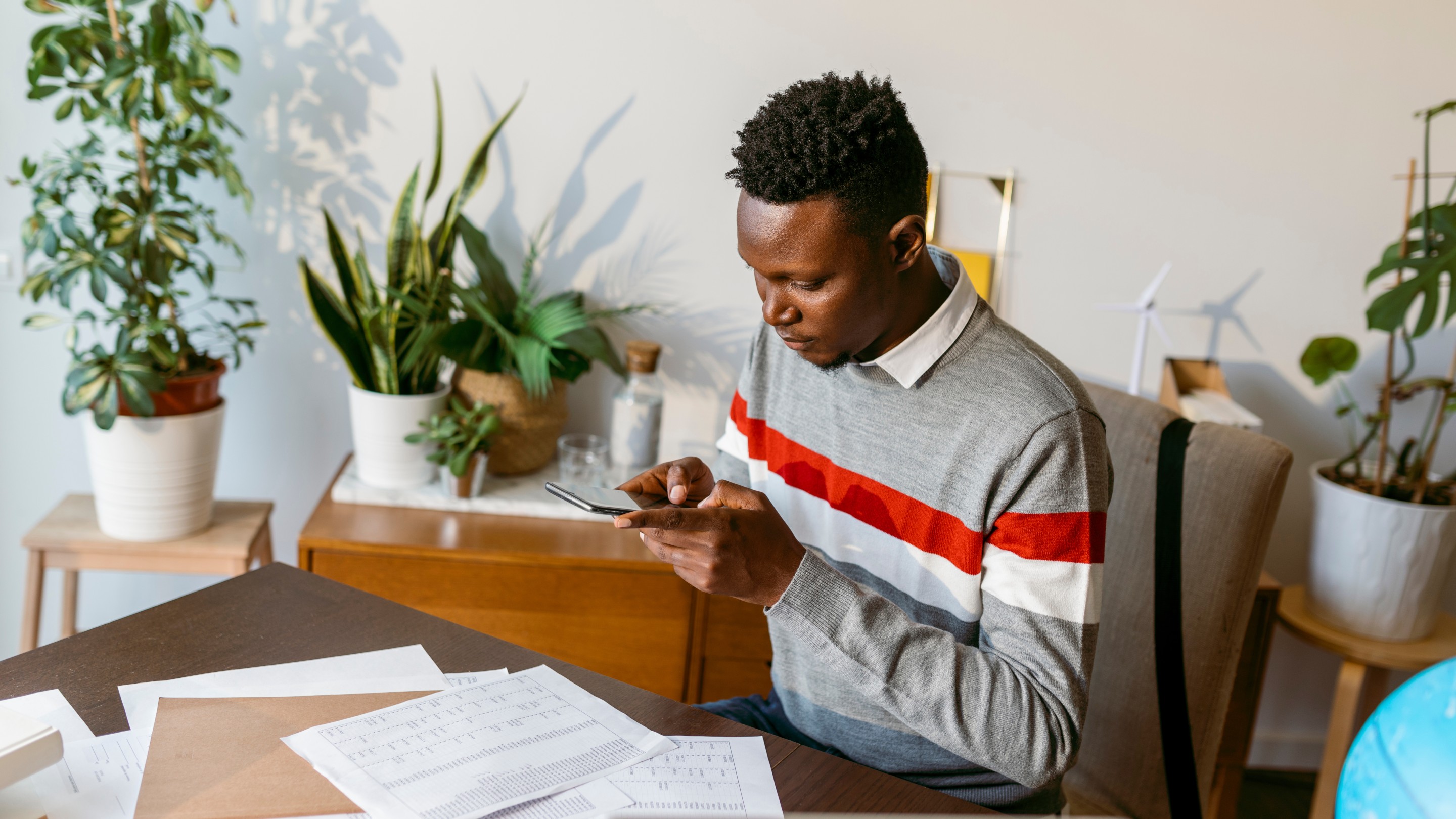 Male taking photo of account document on desk at home office