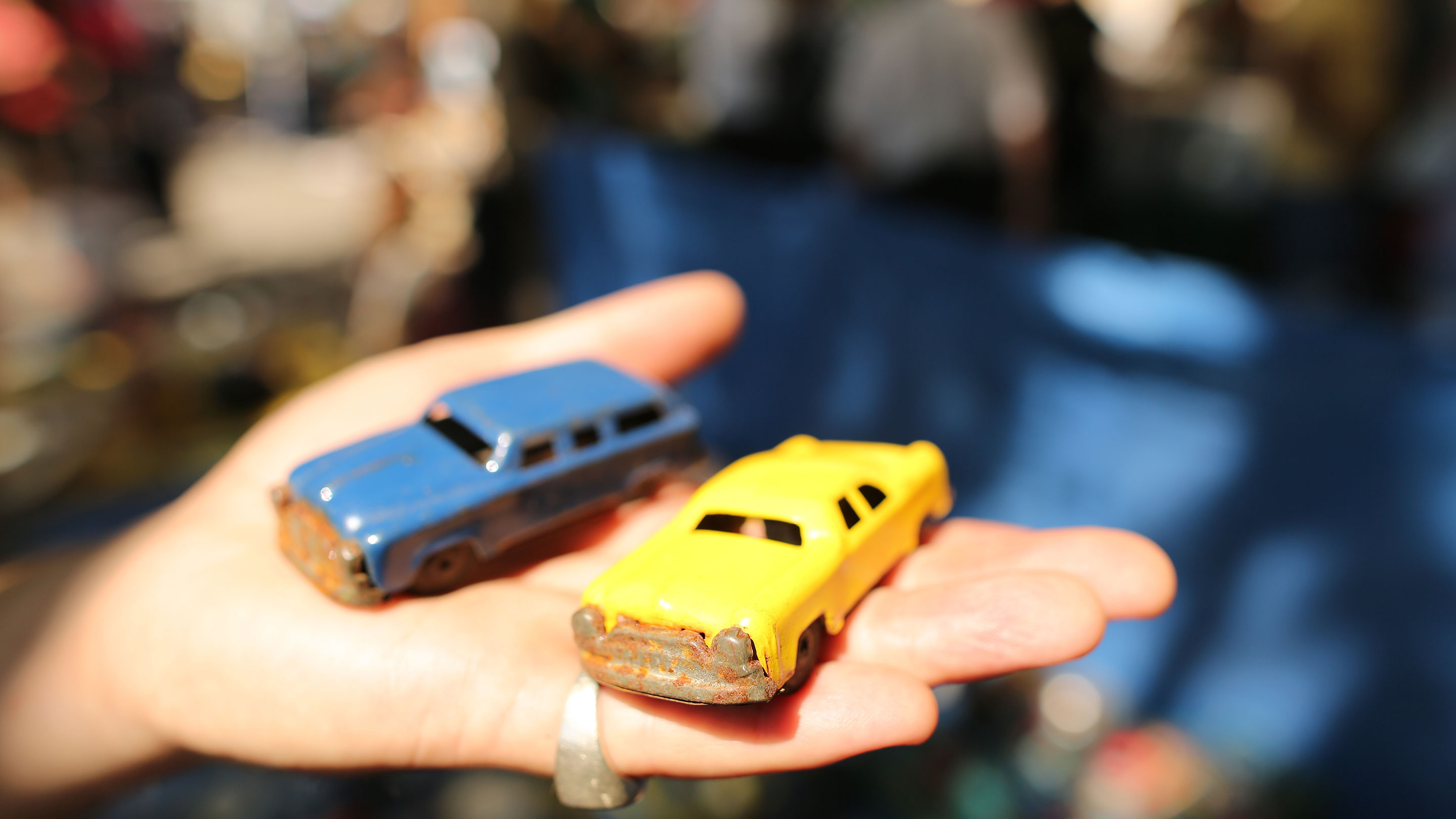 Person holding two toy cars in their hand