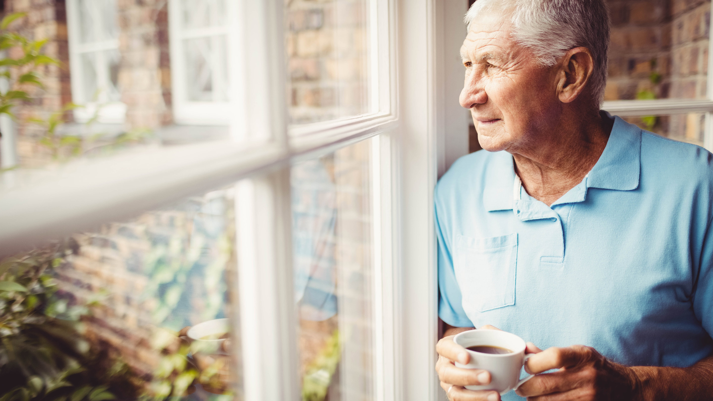 Senior man holding cup and looking out of the window