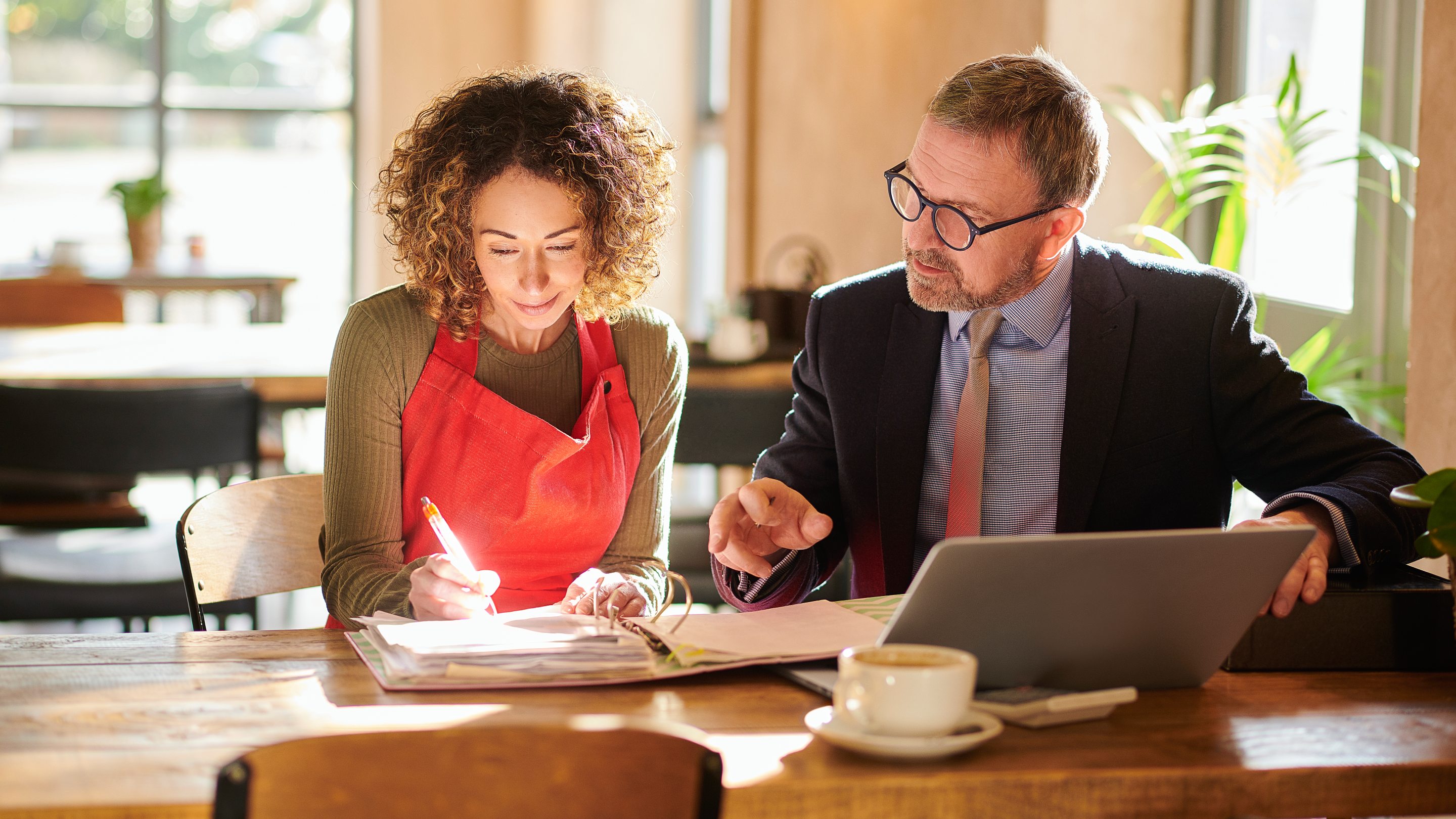 Woman signing business documents with an adviser