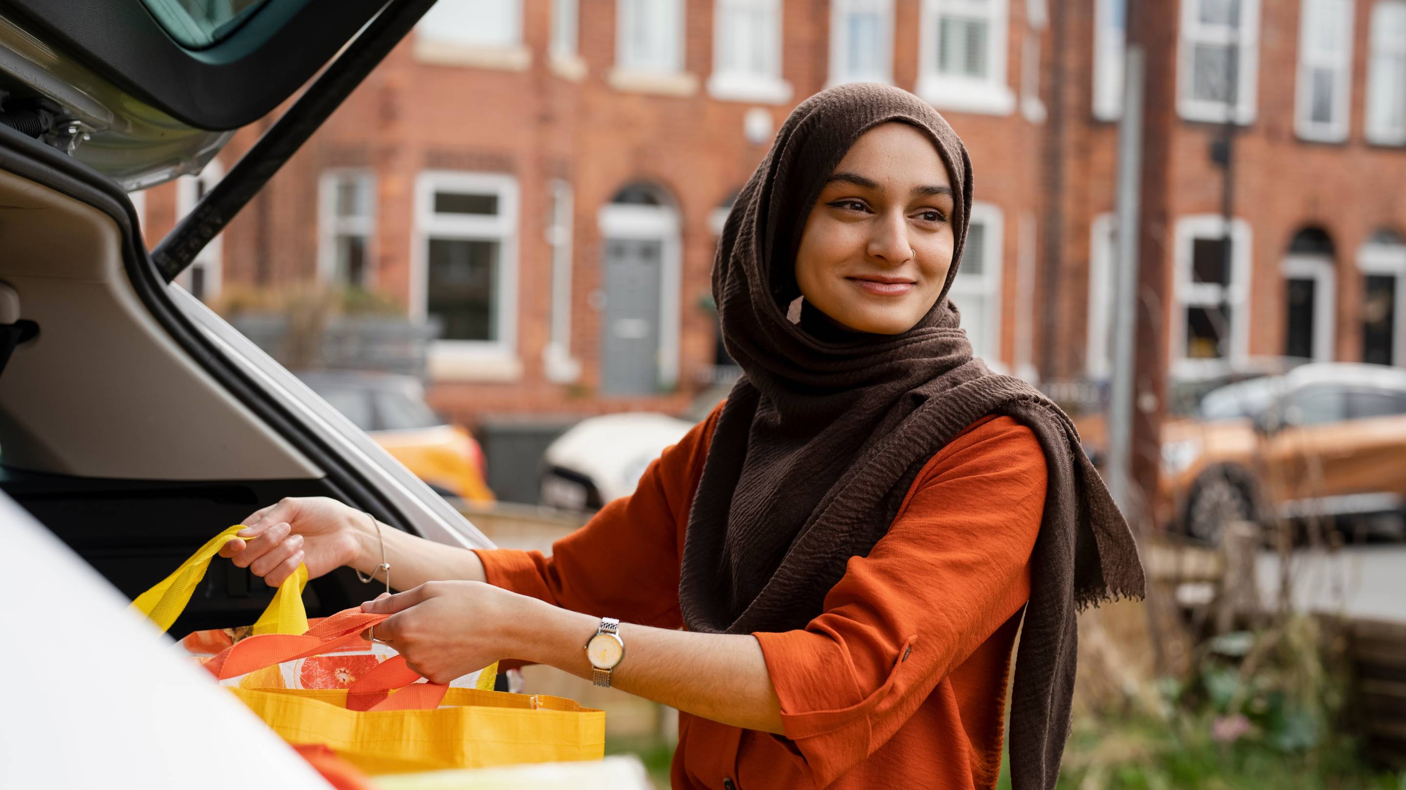 Woman wearing hijab putting shopping in a car