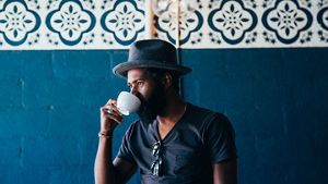 Person wearing a blue hat sipping coffee