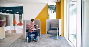 Man sat in an oversized grey chair using a tablet device