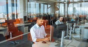 Man sat at a desk in an office at a computer