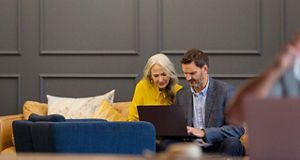 Man and woman looking at a laptop sat on a sofa