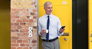 Gentleman browsing his phone whilst on a coffee break