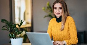 Woman sat at a laptop smiling at the camera