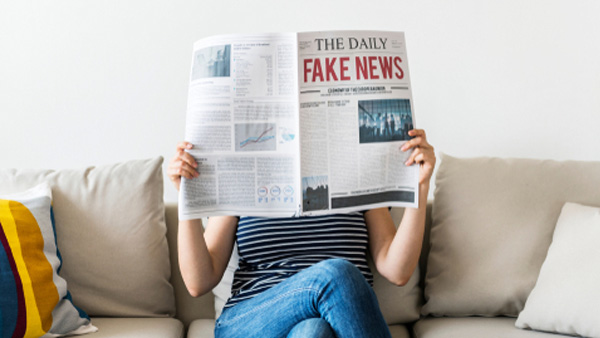 woman reading newspaper with masthead reading 'fake news'