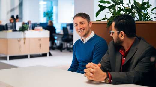 Two male business professionals casually sat together at a lunch table joking together