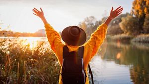 Woman with hands up at sunset
