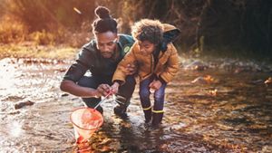 Father and son fishing with net in river