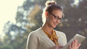 Person standing using a tablet, in an outdoor setting