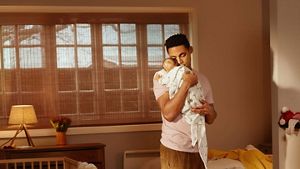 Parent holding their child, who is pointing at something out of shot, with a surprised look on their face