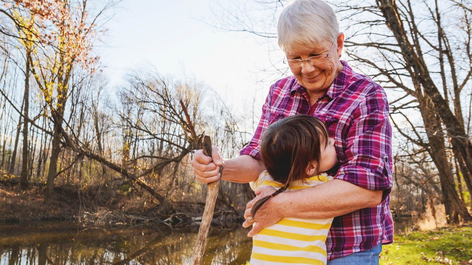 Grandparent being hugged tightly by their loving grandchild, in an outdoor countryside setting