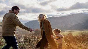 parents with child walking through vast landscape with mountain backdrop