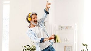Person wearing headphones, dancing happily in their living room, in an indoor setting