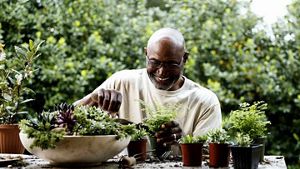 Person smiling whilst planting pot plants, in an outdoor setting