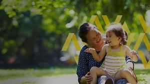 Person with child sitting in a park smiling