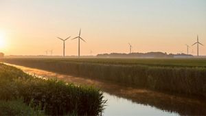 Landscape photo of wind turnbines in the distance, at sunset, in an outdoor setting