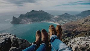 Close crop of two pairs of legs, as a couple are laying down relaxing on a cliff top, admiring the view