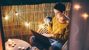 Person in the garden on their laptop drinking coffee