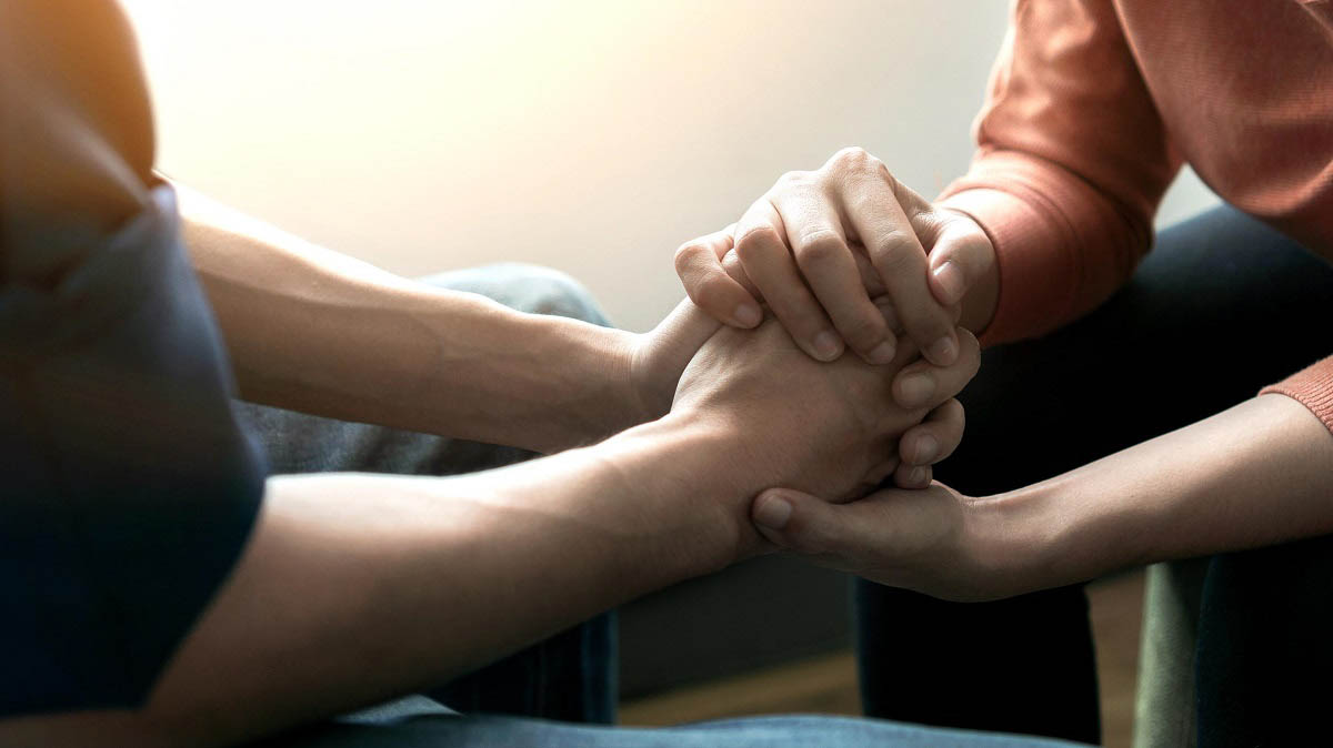 One person holding another person's hand, offering support