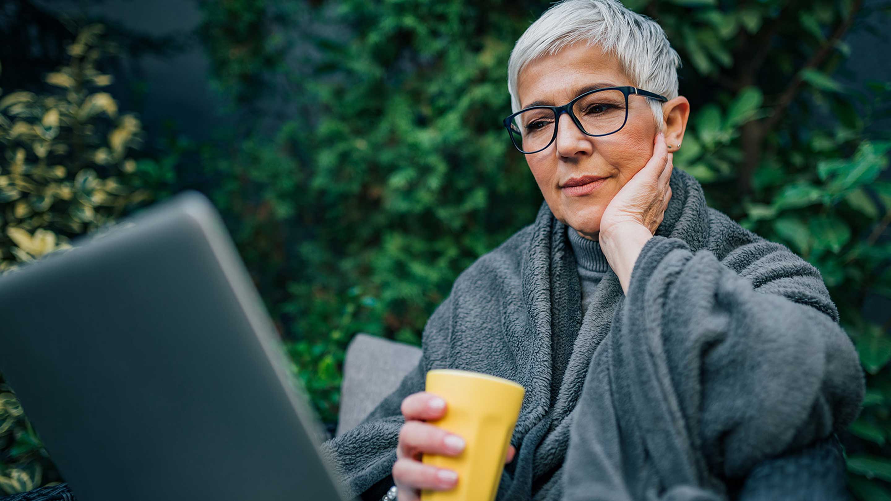 Elderly person on their laptop outdoors