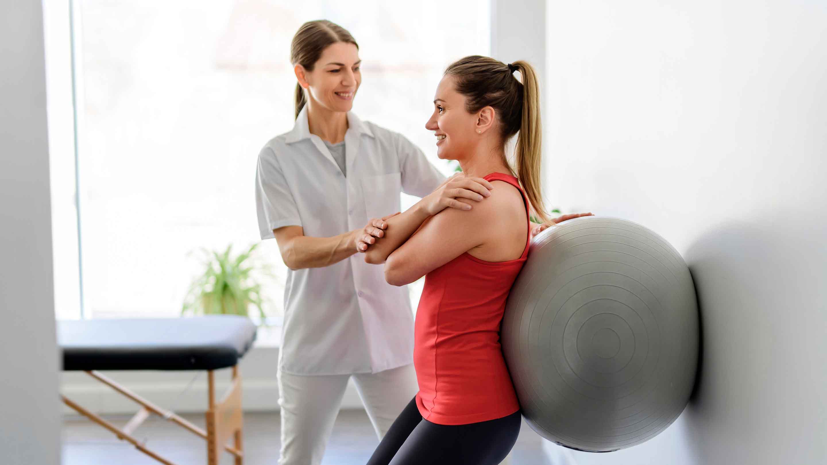 Woman leaning against a balance ball in a physio session