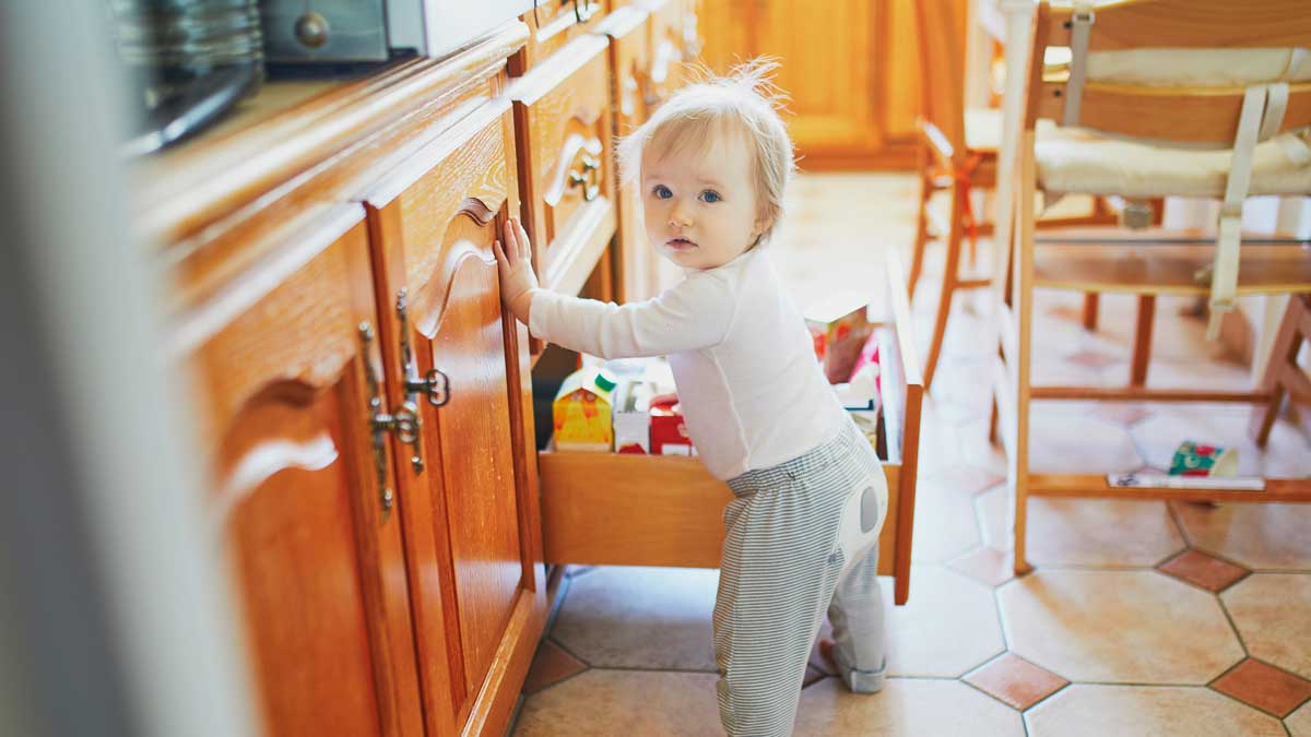 Tips to childproof you home – kid in kitchen pulling out drawer