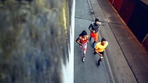 Aerial shot of three people running along a concrete path