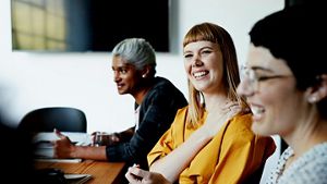 A picture of three women in a meeting room