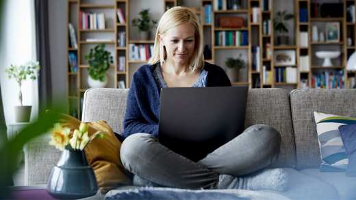A woman sat on sofa, working on laptop.