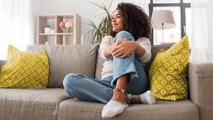 happy young woman sitting on sofa at home