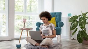 Women sitting on floor in home, working on laptop