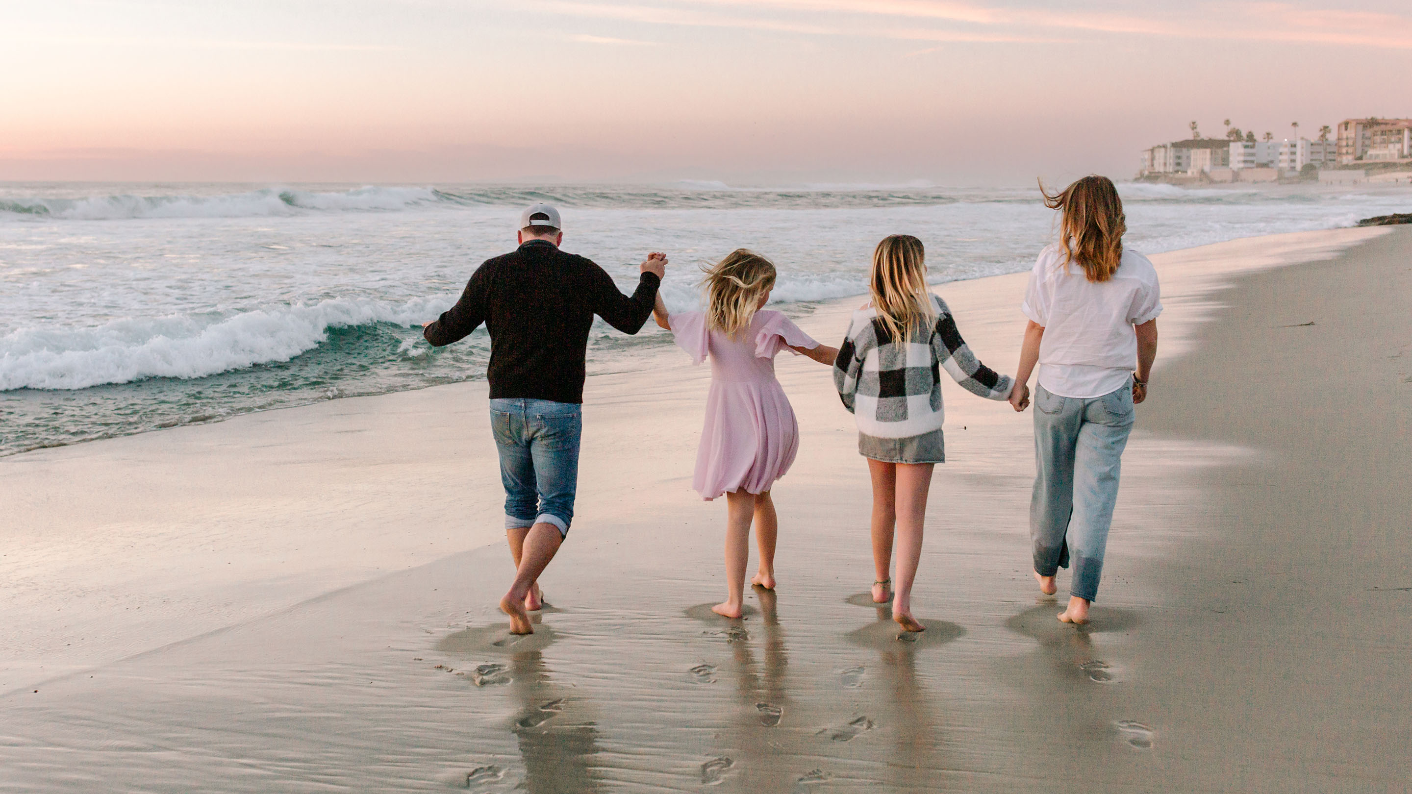 Family with teenagers on the beach together at sunset