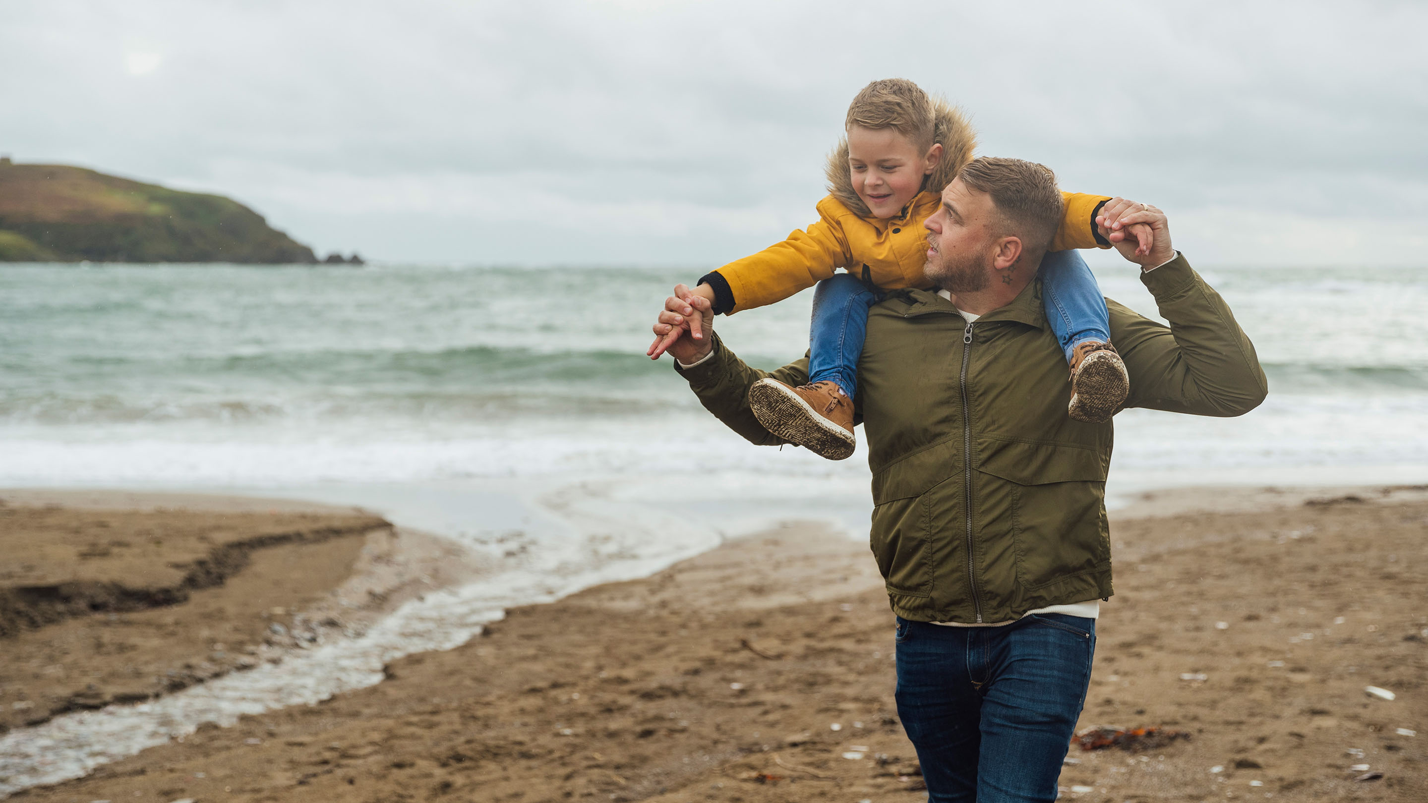 Father carrying his son on his shoulders on an autumnal beach