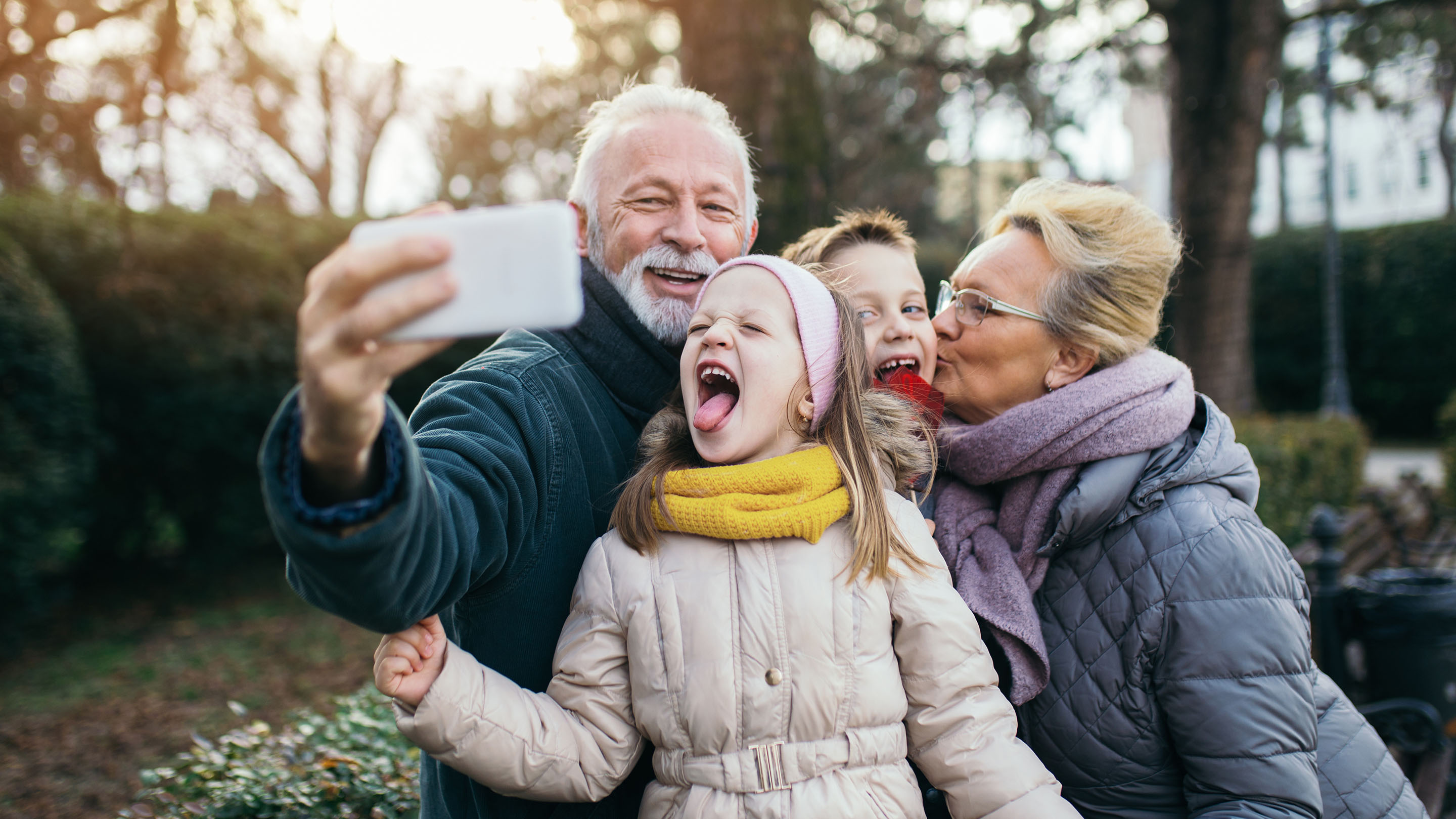 Grandparents taking selfie with grandchildren in park