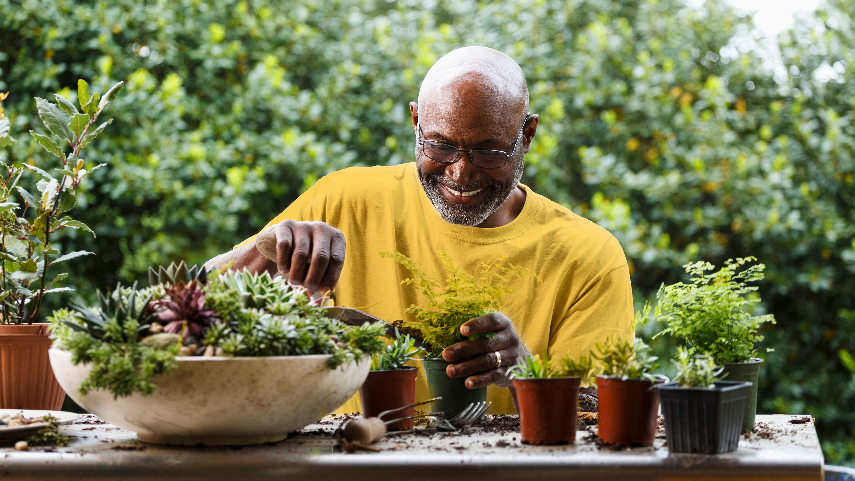 Man potting plants at table in garden